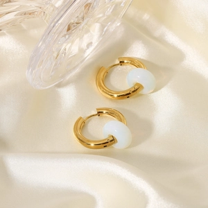 Detail of 18K gold stainless steel earrings with white opal beads on satin fabric