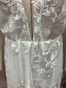 Detailed view of V-neck white lace embroidery and tulle layers on bridal gown
