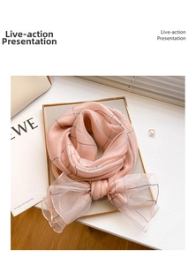 Macro detail of soft pink plaid silk wool scarf draped elegantly on a gold tray