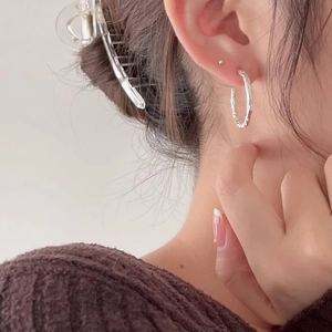 Minimalist 925 sterling silver hoop earrings with hammered texture worn by a model