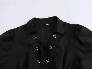 Close-up of black polo dress neckline with gold eyelets and lace-up drawstring design