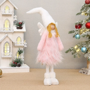 Détail d'une poupée ange en peluche rose avec bonnet blanc et cheveux dorés festifs