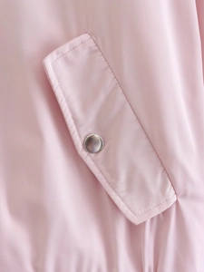 Detail shot of a pink bomber jacket featuring a metal snap button and twill fabric texture