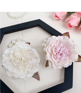 Detail of white and pink fabric flowers with pearl clusters on a black hexagon frame