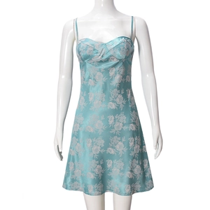 Detail of mint green satin dress featuring delicate white floral patterns and silky texture