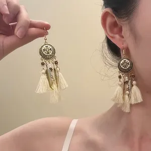 Detail of vintage gold flower earrings with wooden beads and long cream cotton tassels
