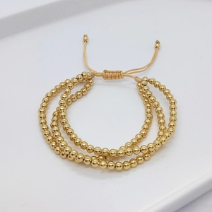 Detailed close-up of 4mm gold plated copper beads with adjustable braided cord pull-tie