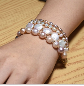 Detail of layered baroque pearl bracelet featuring pink and white pearls with gold beads