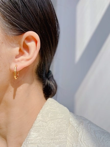 Detail view of gold-plated bamboo texture hoop earrings worn on a model's ear