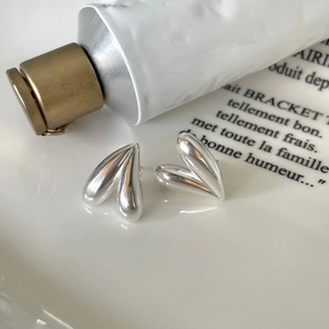 Polished 925 sterling silver heart-shaped stud earrings on a white porcelain plate
