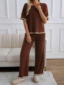 Detail of dark brown knit set featuring short sleeve top and wide leg pants with beige trim
