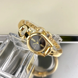 Detail of gold horsebit bracelet watch featuring a black dial and sleek metallic finish