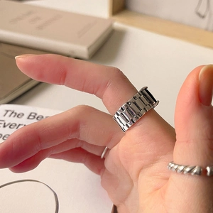 Close-up of wide silver ring with watch band texture on a model's finger
