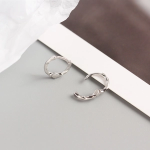 Macro detail of silver twisted knot hoop earrings with textured spiral design