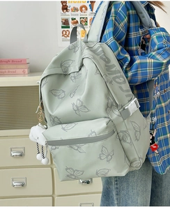 Detailed side view of light green butterfly print backpack with a cute cloud keychain