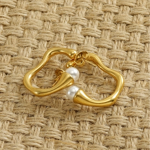 Macro view of irregular gold earrings with pearls on a woven texture background