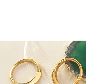 Minimalist 18K gold-plated titanium steel rings displayed on green agate stone base