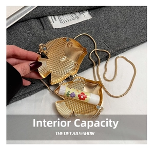 Detail showing internal capacity of the golden fish-shaped metal lipstick bag with chain