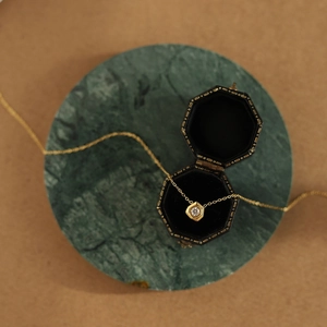Macro detail of geometric hexagonal pendant necklace with a round diamond on velvet box