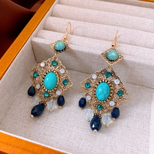 Détail de boucles d'oreilles vintage en or avec pierre turquoise et glands en cristal
