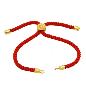 Detail of adjustable red braided cord bracelet with a sliding gold tree pattern charm