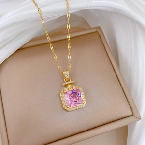 Gros plan détaillé du collier flacon de parfum doré avec cristal rose sur soie blanche
