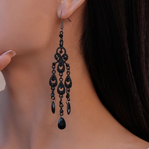Detail of vintage black teardrop earrings with crystals worn by a model in soft light