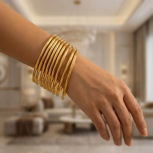 Close-up of 3mm gold stainless steel stackable bangles worn by a model in warm light
