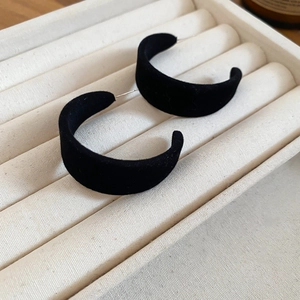 Gros plan de boucles d'oreilles en velours noir en forme de C dans un coffret
