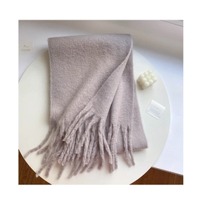Detail showing plush light purple knit scarf with fringe tassels on white table