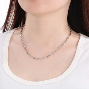 Detail of silver oval link chain necklace worn by a model for a minimalist fashion look