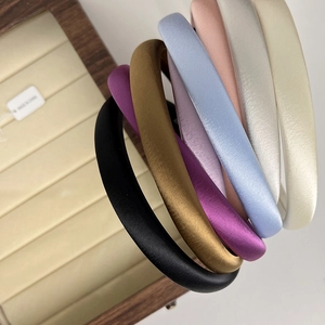 Macro detail of multi-color satin padded headbands displayed on a wooden jewelry tray