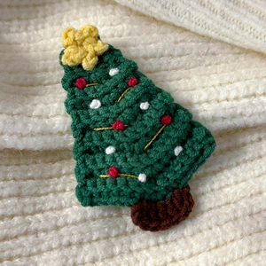 Detailed macro view of a handmade knitted Christmas tree hair clip with soft yarn texture