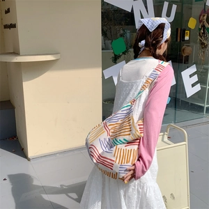 Colorful striped canvas hobo bag worn as a crossbody bag for daily urban commuting