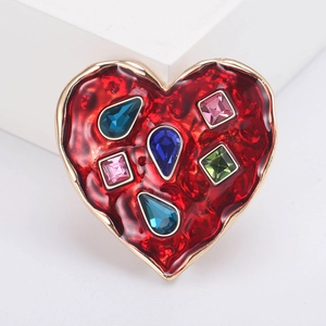 Macro shot of a vintage heart brooch with red enamel and vibrant multi-colored gemstones