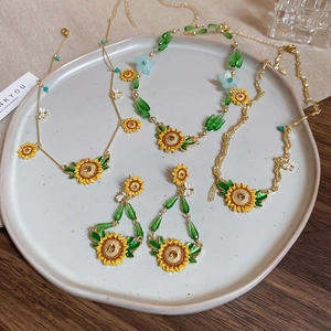 Detailed set of sunflower and bee jewelry with gold enamel finish and green crystals