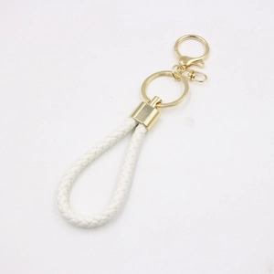 Detailed view of white braided leather keychain with polished gold metal lobster clasp