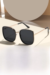 Detail of black oversized sunglasses with slim gold metal temples and UV protection lens