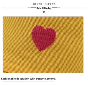 Detail view of pink heart embroidery on yellow cotton fabric of the sun bucket hat