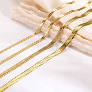 Flat gold snake bone chain necklace in various widths on elegant silk background