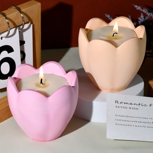 Primer plano de vela aromática en forma de tulipán rosa sobre soporte decorativo