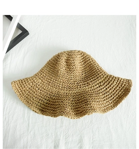 Detailed top view of natural straw weaving texture and sun hat craftsmanship on white fabric