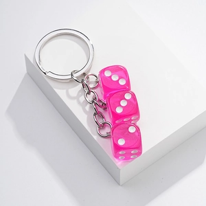 Detail of rose red translucent dice keychain with silver rings on a white display pedestal