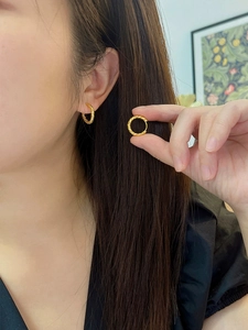 Macro detail of French vintage golden twisted rope hoop earrings worn by a model