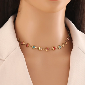 Golden heart link necklace with red and blue gemstones worn by a model for fashion
