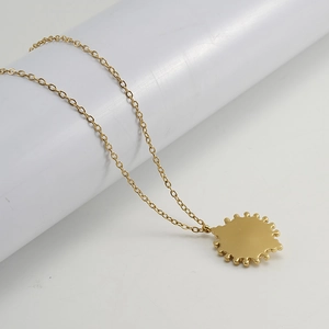 Macro view of gold stainless steel necklace featuring a radiant sun-shaped pendant detail