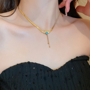 Detail of gold fan-shaped earring with blue gemstone and elegant tassel chains on a model