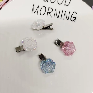 Aurora camellia hair clips in iridescent resin, set of four on a white ceramic plate