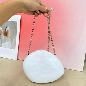 Detail of white marble acrylic clutch bag with a slim silver metal chain strap