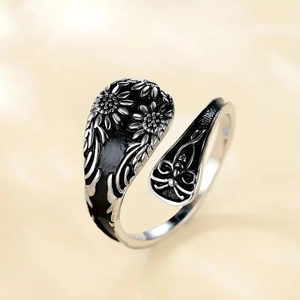 Close-up of vintage sunflower embossed silver ring with oxidized details and open band